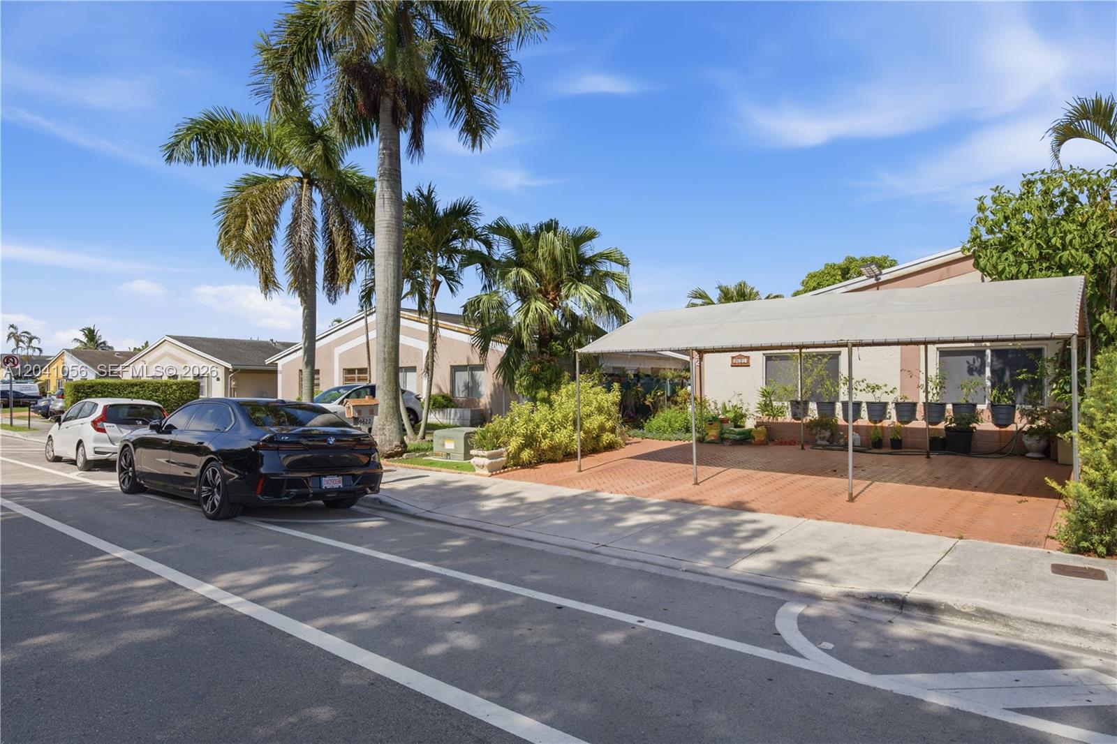 A single-story house with a paved carport and palm trees sits along a residential street — 9622 SW 146th Ave, Miami FL 33186, MIAMI, FL