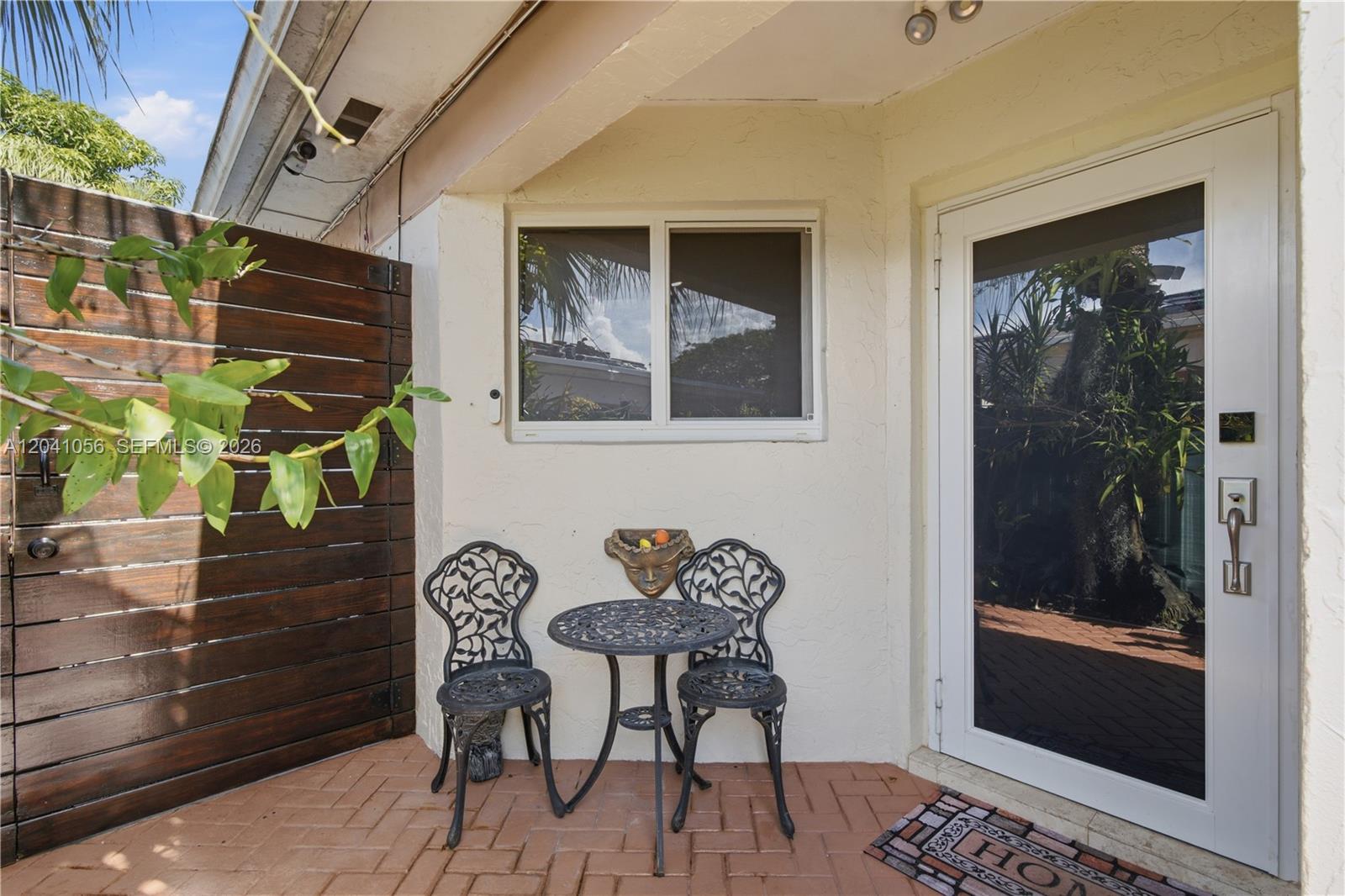 A small patio features a bistro set, a wall-mounted decorative mask, and a glass door — 9622 SW 146th Ave, Miami FL 33186, MIAMI, FL