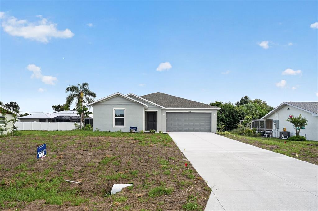 A single-story gray house with a two-car garage and an unfinished front yard — 22568 ALCORN AVENUE, PORT CHARLOTTE, FL