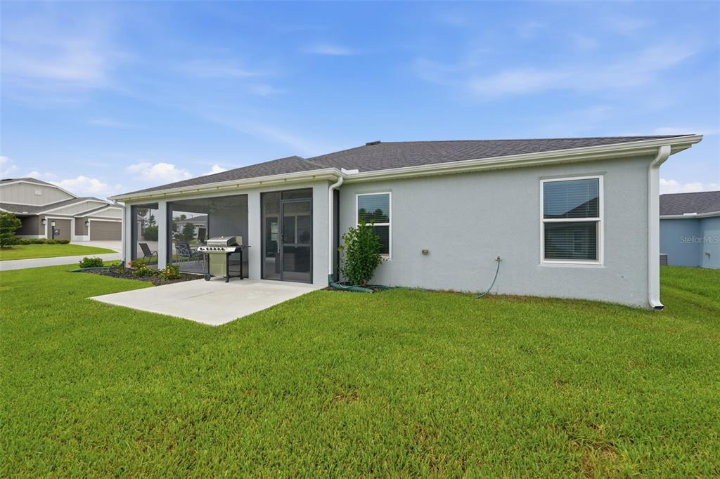 A gray house exterior features a screened-in patio, a concrete slab, and a grassy yard — 2006 OPPENHEIMER COURT, THE VILLAGES, FL