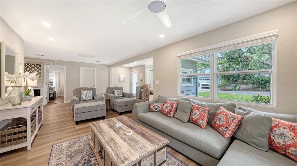 A living room features a gray sectional sofa, two armchairs, a wooden coffee table, and windows — 1773 HARMONY LANE, SARASOTA, FL