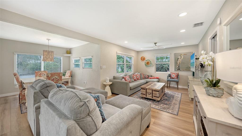 A living room with gray sectional sofas, a wooden coffee table, and an adjacent dining area — 1773 HARMONY LANE, SARASOTA, FL