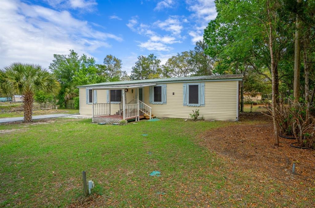 A single-story mobile home with light yellow siding and a front porch sits on grass — 5415 S DOYLE TERRACE, HOMOSASSA, FL