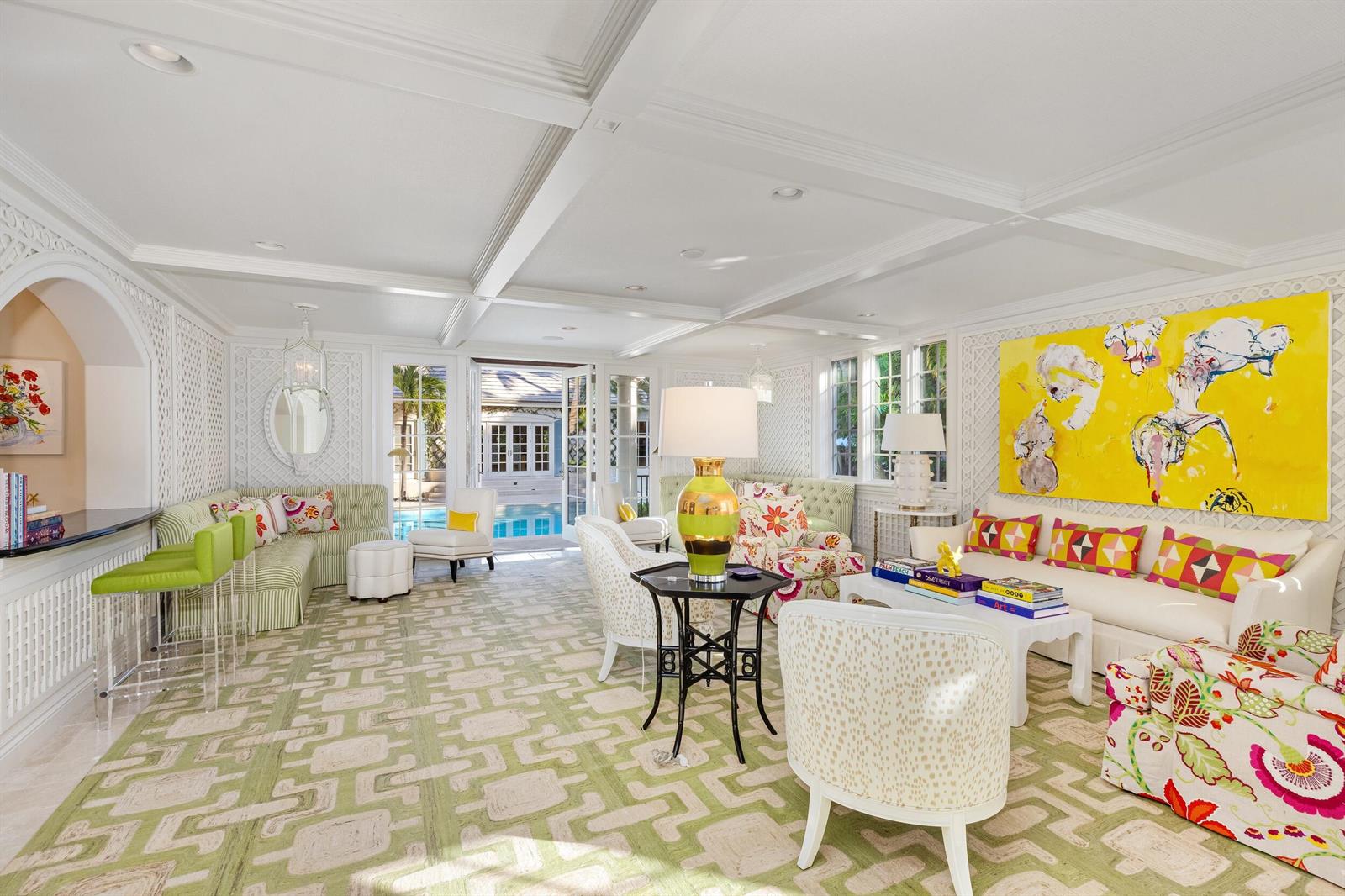 A bright living room features a green patterned rug, white lattice walls, and yellow artwork — 9 Via Vizcaya, Palm Beach FL 33480, PALM BEACH, FL