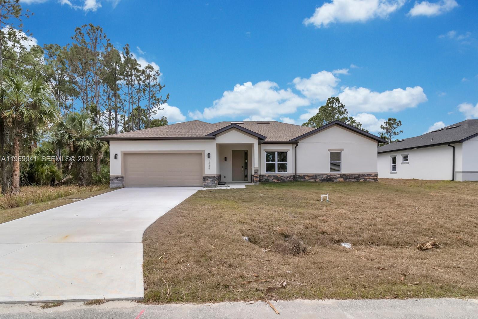 A single-story house with a beige stucco exterior, stone accents, and a two-car garage — 1821 MISSOURI, Palm Bay FL 32907, PALM BAY, FL