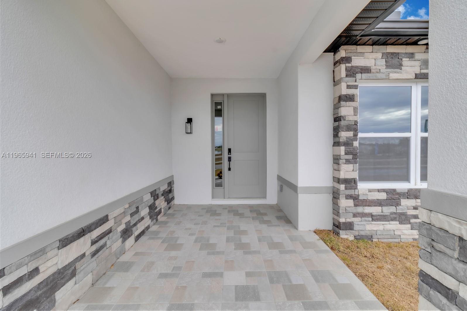 A covered entryway features a gray front door, stone veneer accents, and tiled flooring — 1821 MISSOURI, Palm Bay FL 32907, PALM BAY, FL