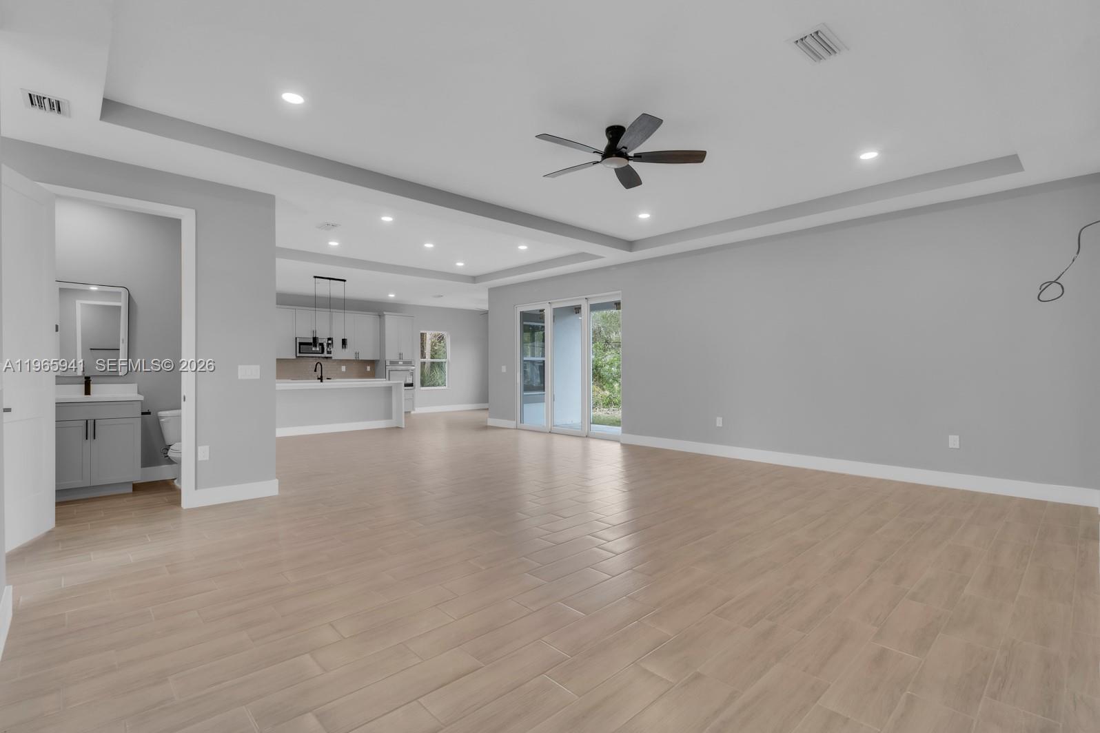An open-concept living area features light wood-look tile flooring, a tray ceiling, and a kitchen — 1821 MISSOURI, Palm Bay FL 32907, PALM BAY, FL