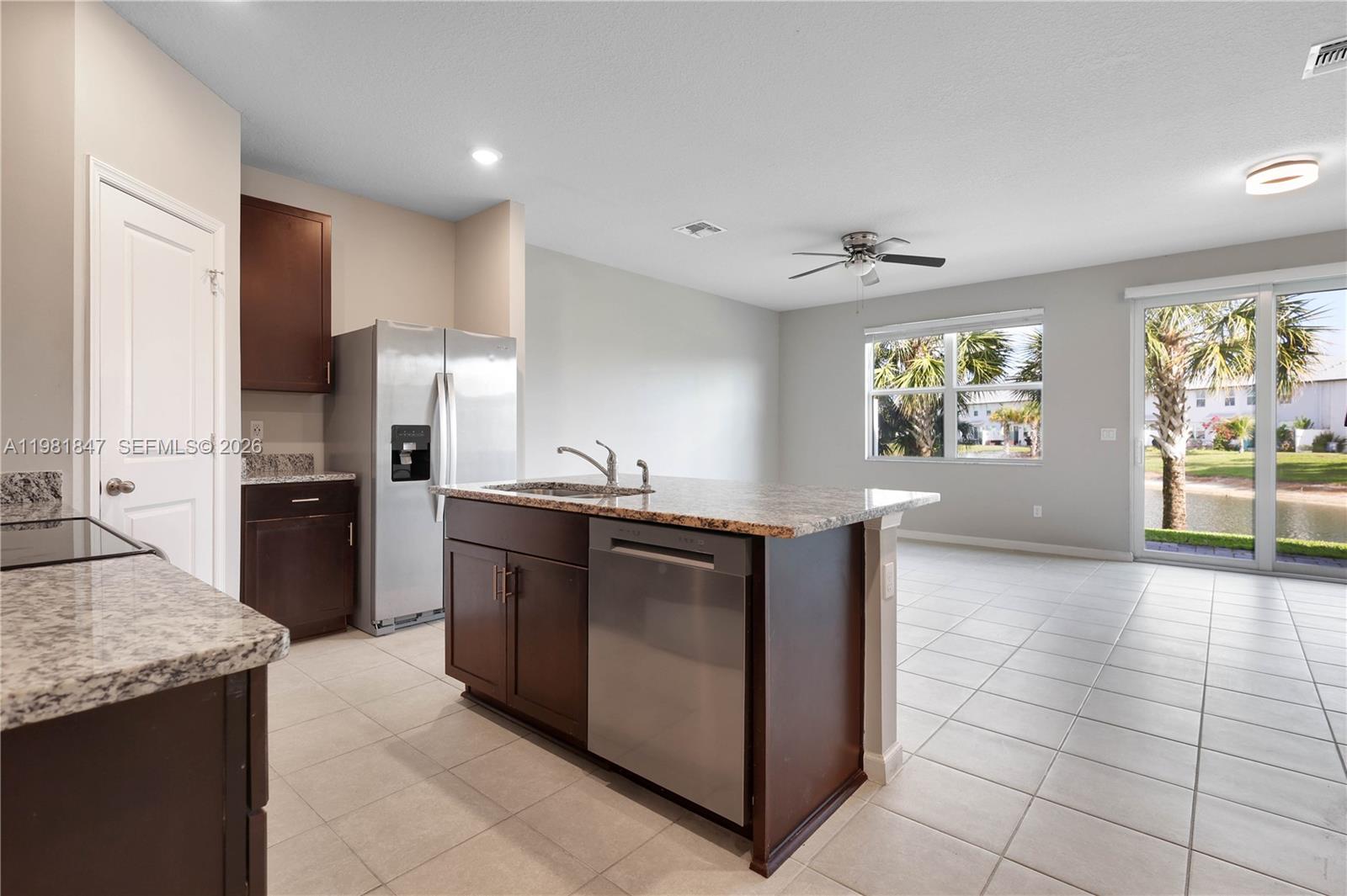 A kitchen with dark wood cabinets, granite countertops, and stainless steel appliances overlooks a lake — 1761 Lindley St, Mangonia Park FL 33407, MANGONIA PARK, FL