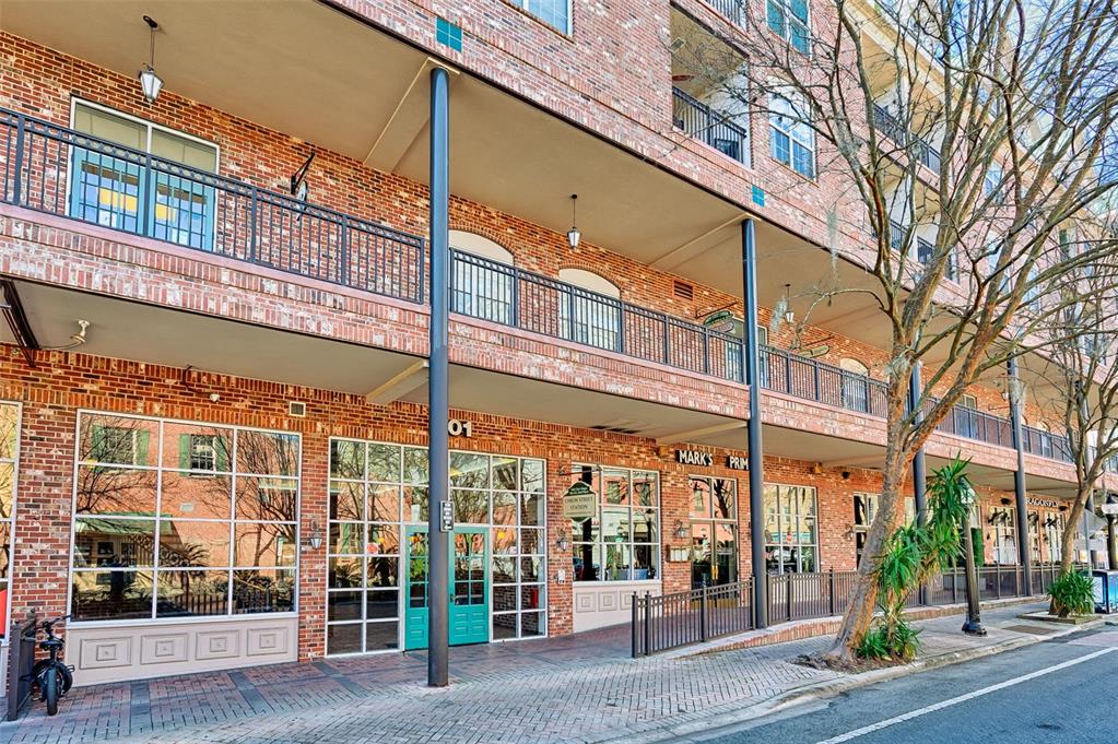 A multi-story brick building features ground-level storefronts, a second-floor balcony, and large glass windows — 201 SE 2ND AVENUE UNIT 317, GAINESVILLE, FL