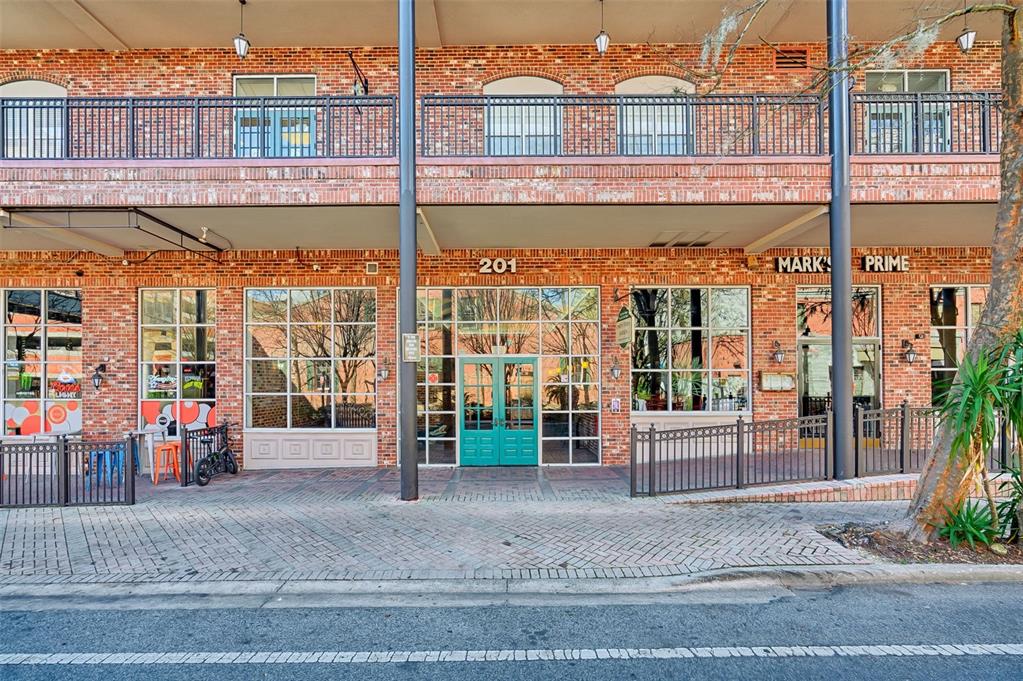 The exterior of a brick building features a ground-level storefront with teal double doors — 201 SE 2ND AVENUE UNIT 317, GAINESVILLE, FL