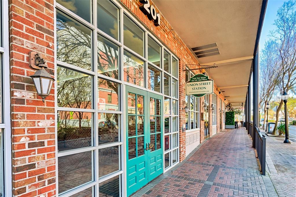 A brick building exterior features a teal double door entrance and a hanging station sign — 201 SE 2ND AVENUE UNIT 317, GAINESVILLE, FL