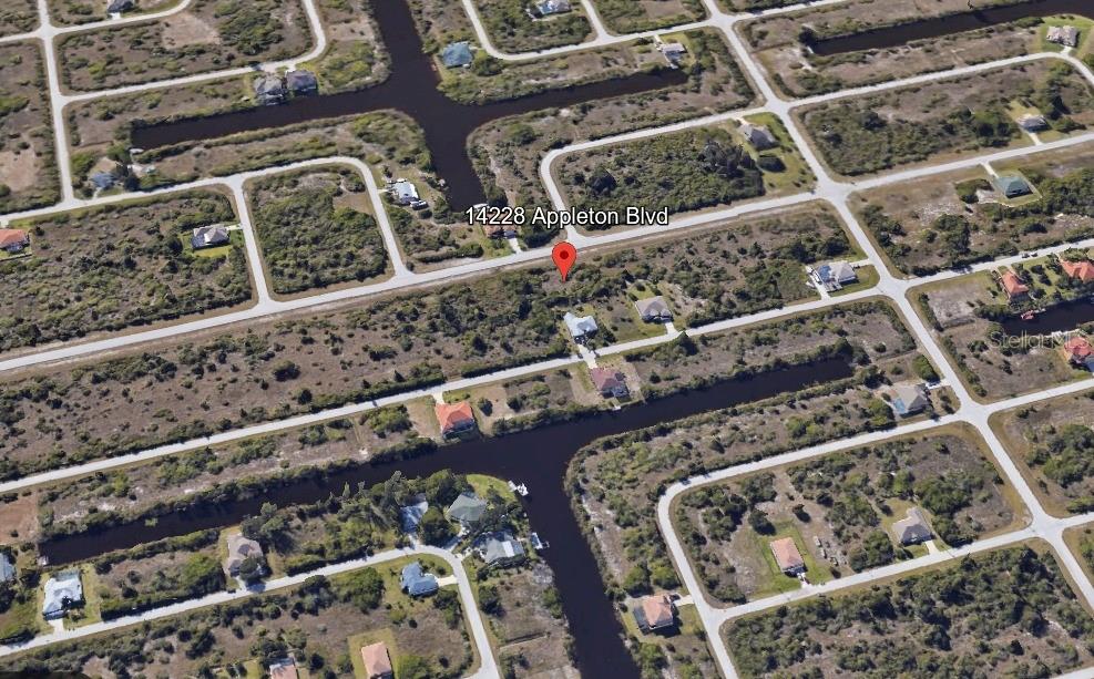 An aerial view shows a residential lot with a house surrounded by canals and vegetation — 14228 APPLETON BOULEVARD, PORT CHARLOTTE, FL