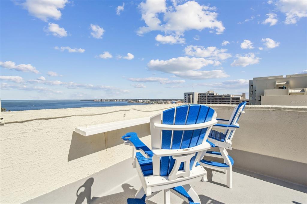 Two blue and white Adirondack chairs sit on a balcony overlooking the ocean — 5915 SEA RANCH DRIVE UNIT 703, HUDSON, FL