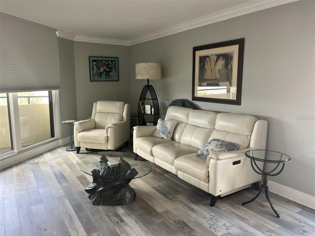 A living room features light-colored leather seating, a glass coffee table, and wood-look flooring — 5915 SEA RANCH DRIVE UNIT 703, HUDSON, FL