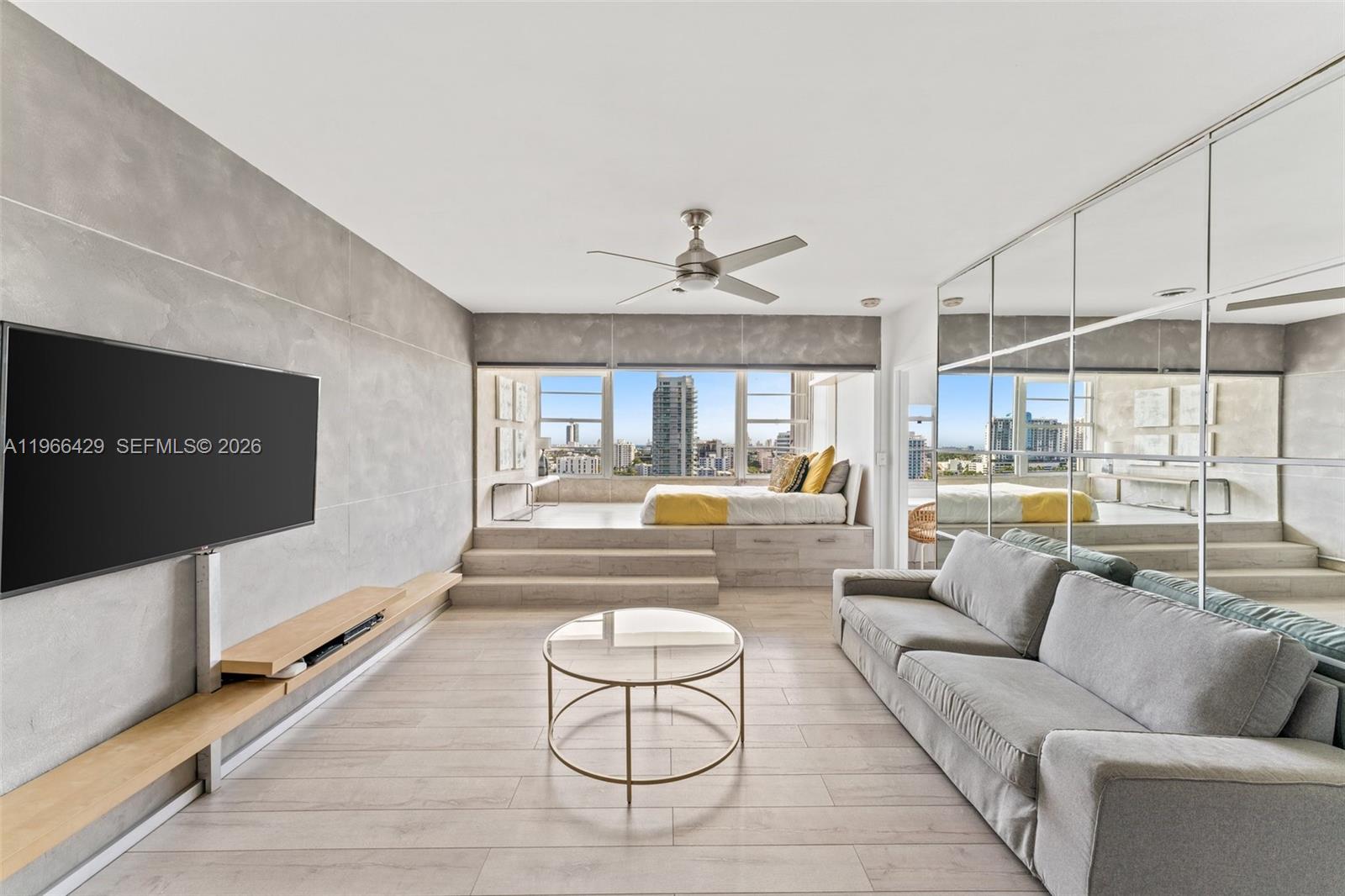 A living room features a raised platform bed, a gray sofa, and a mirrored wall — 3 Island Ave, Miami Beach FL 33139, MIAMI BEACH, FL