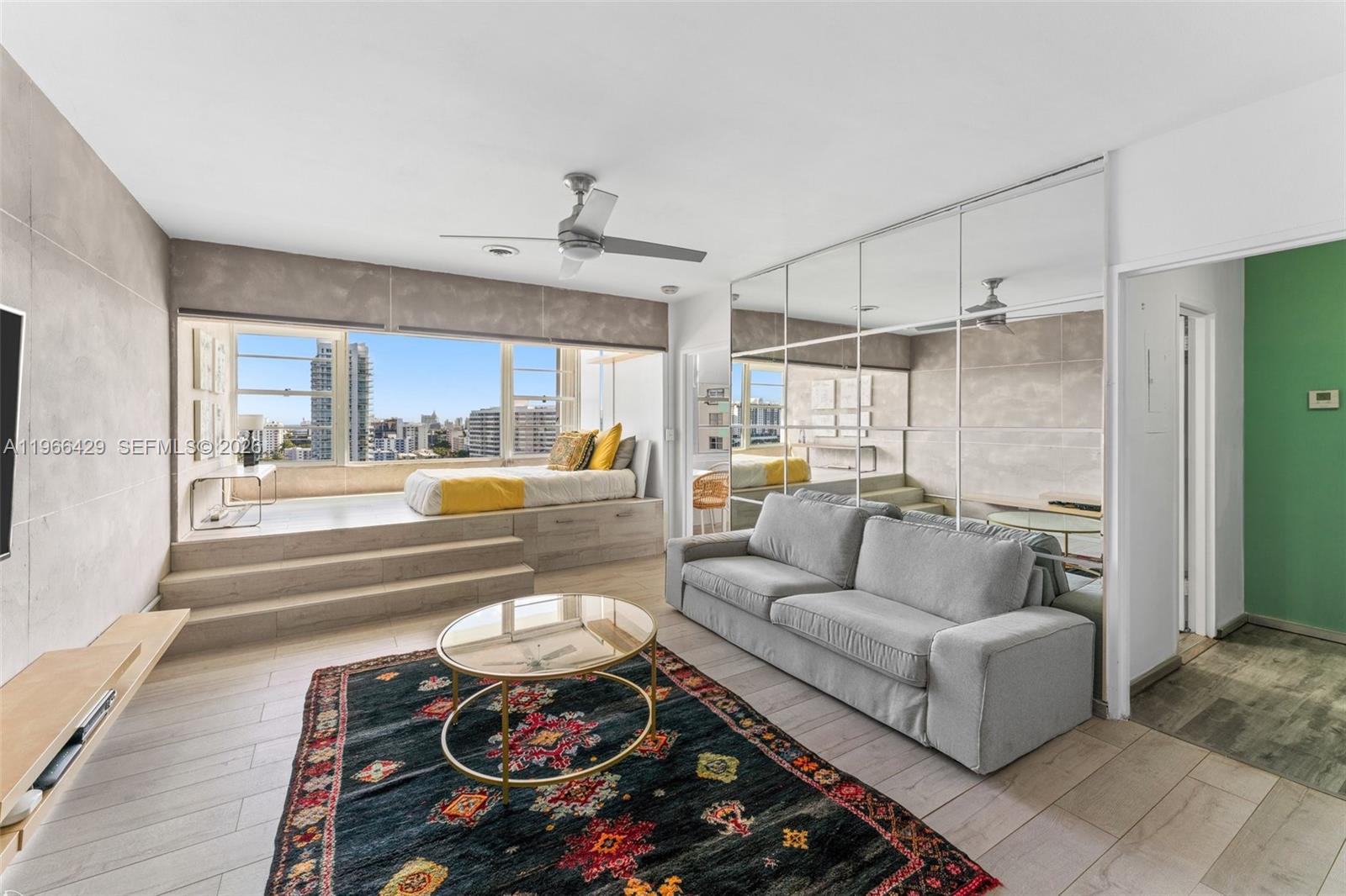 A living room features a raised platform bed by a window, mirrored walls, and a sofa — 3 Island Ave, Miami Beach FL 33139, MIAMI BEACH, FL