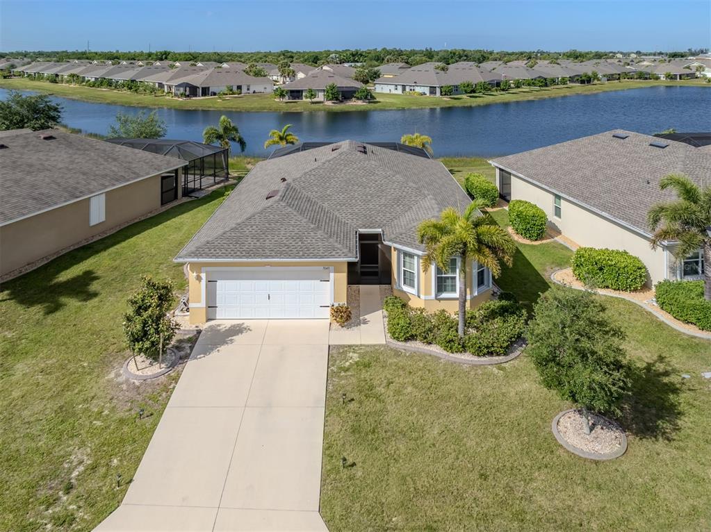 An aerial view shows a single-story house with a tan exterior, gray roof, and driveway — 7045 WATERFORD PARKWAY, PUNTA GORDA, FL