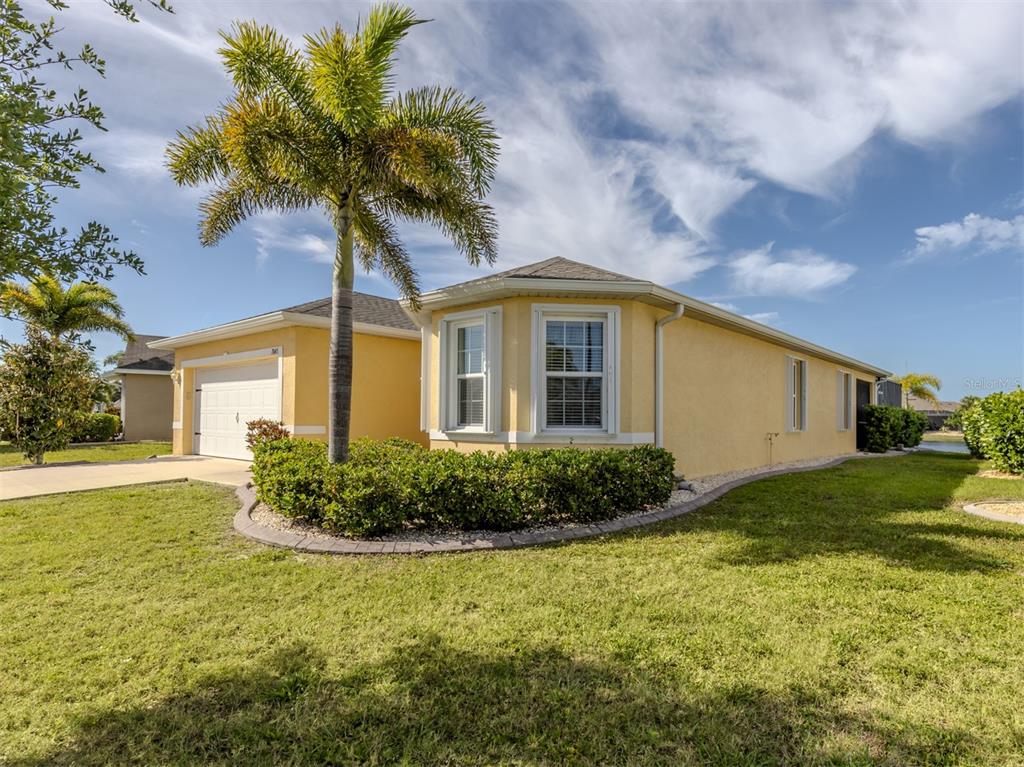 A yellow single-story house with a palm tree, a garage, and a landscaped front yard — 7045 WATERFORD PARKWAY, PUNTA GORDA, FL
