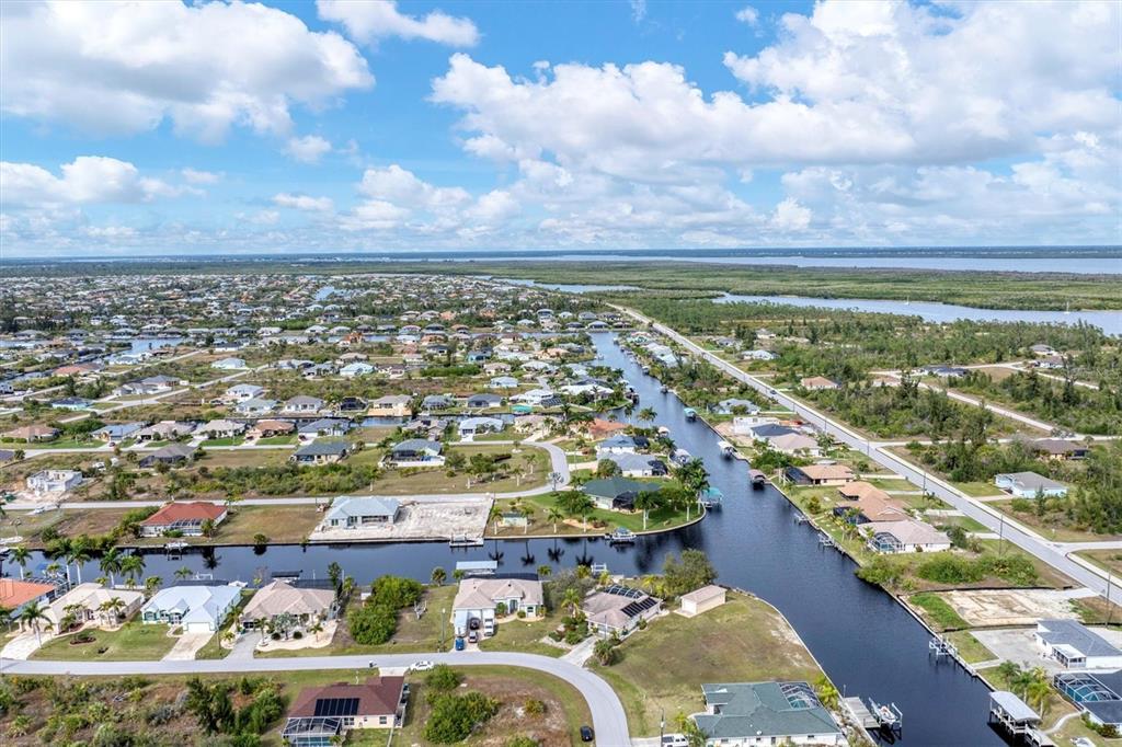An aerial view shows residential houses along a canal in a coastal neighborhood — 15500 LONGVIEW ROAD, PORT CHARLOTTE, FL