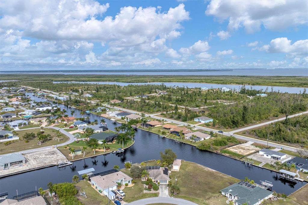 An aerial view shows a residential neighborhood with houses situated along a network of canals — 15500 LONGVIEW ROAD, PORT CHARLOTTE, FL
