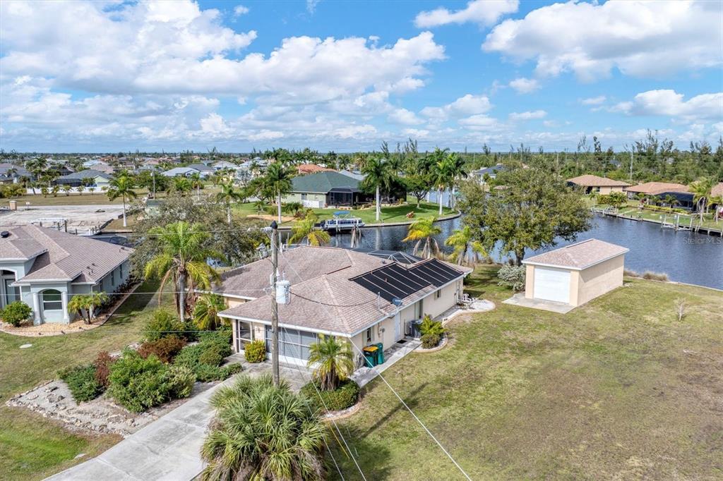 An aerial view shows a house with solar panels, a detached garage, and a canal — 15500 LONGVIEW ROAD, PORT CHARLOTTE, FL