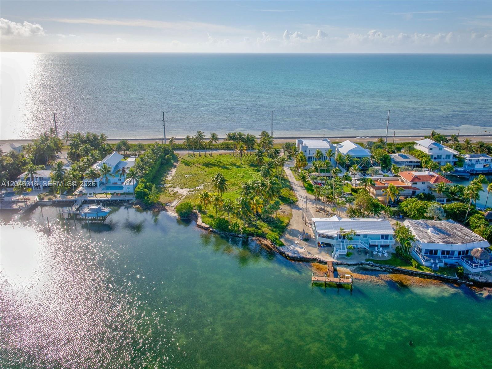 An aerial view shows waterfront homes, a vacant grassy lot, and a boat dock — 74900 Overseas Hwy, Islamorada FL 33036, ISLAMORADA, FL