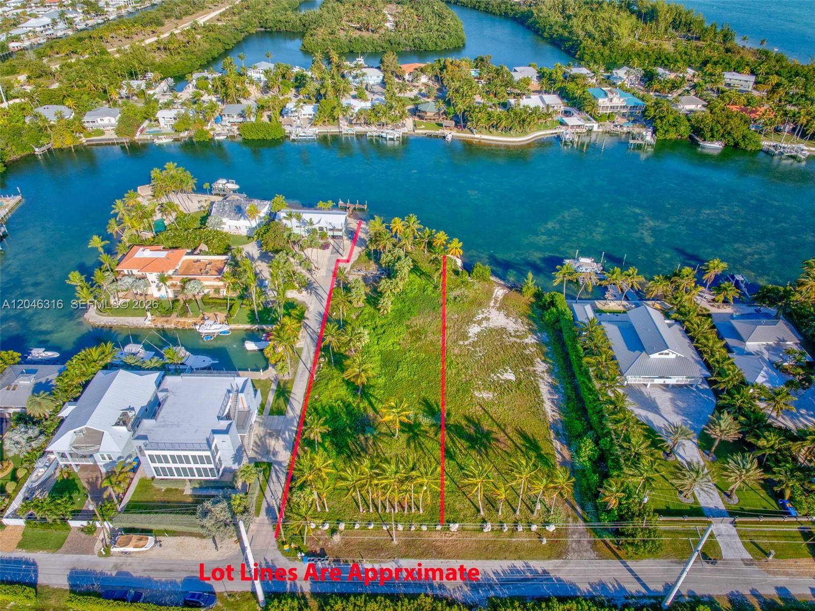 An aerial view shows a vacant waterfront lot marked by red lines between two houses — 74900 Overseas Hwy, Islamorada FL 33036, ISLAMORADA, FL
