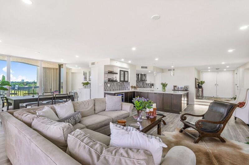 An open-concept living and dining area features a large sectional sofa and a kitchen island — 1900 Consulate Place # 406, West Palm Beach FL 33401, WEST PALM BEACH, FL