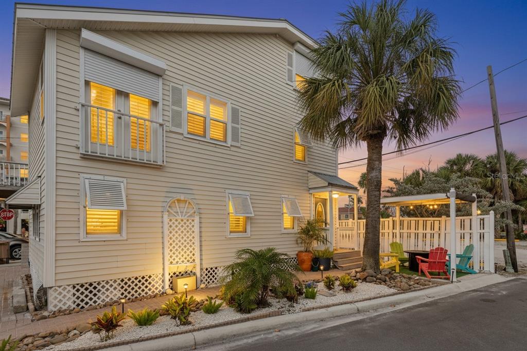 A two-story, light-colored house with a balcony, palm tree, and outdoor patio area — 13095 GULF LANE, MADEIRA BEACH, FL