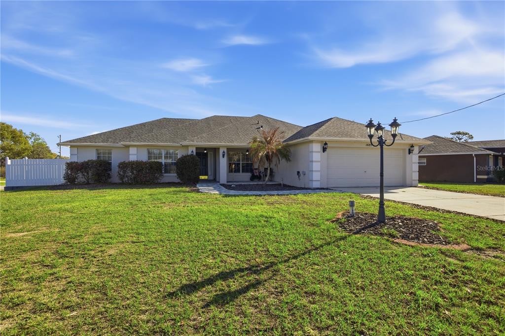 A single-story house with a light-colored exterior, a two-car garage, and a large front lawn — 14185 DORADO STREET, SPRING HILL, FL
