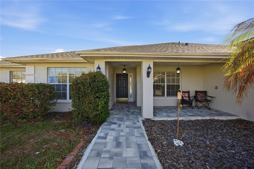 A single-story house exterior features a paved walkway leading to a covered front porch entrance — 14185 DORADO STREET, SPRING HILL, FL