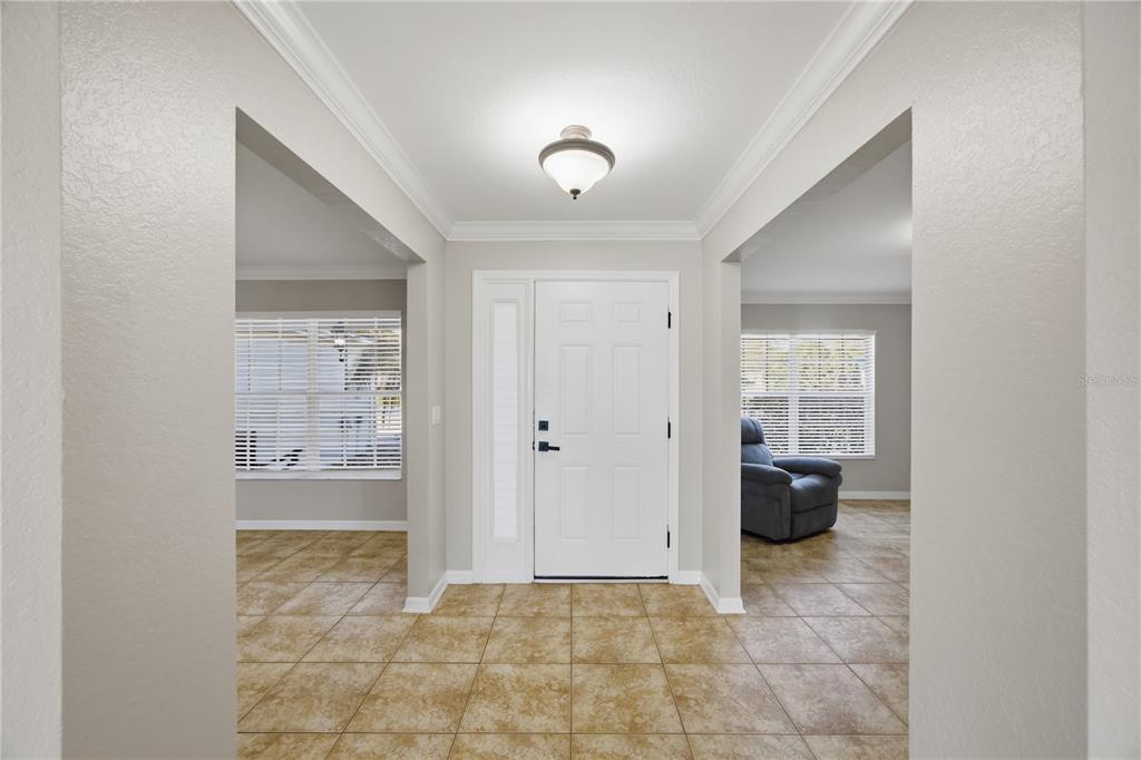 A tiled entryway features a white front door with a sidelight and two adjacent rooms — 14185 DORADO STREET, SPRING HILL, FL
