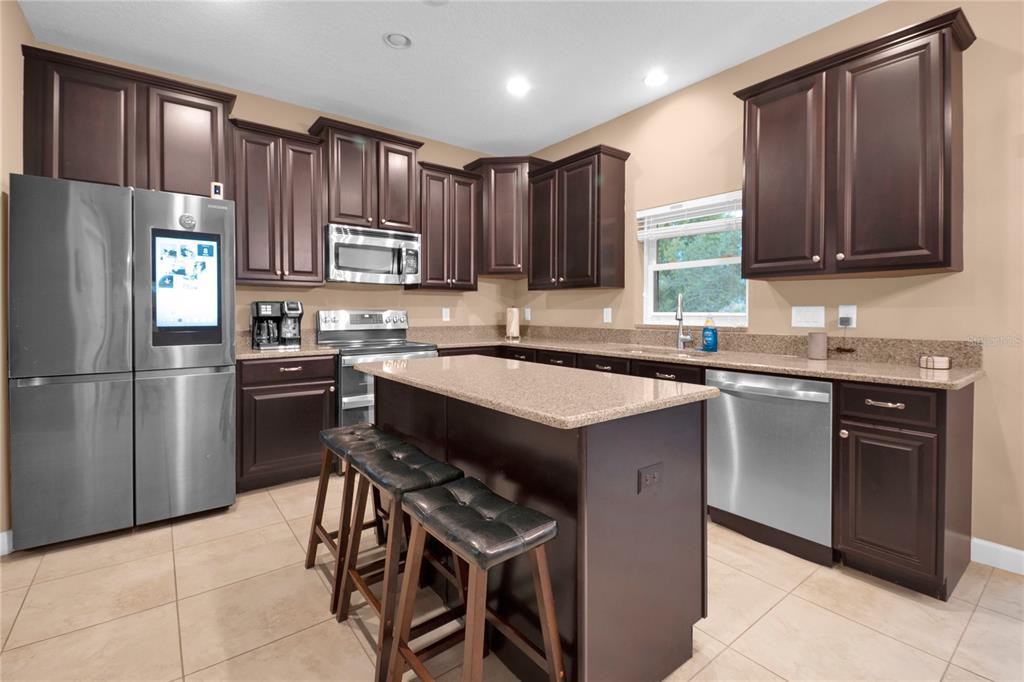 A kitchen with dark wood cabinets, granite countertops, stainless steel appliances, and a central island — 1301 GLENEAGLES LANE, DAVENPORT, FL