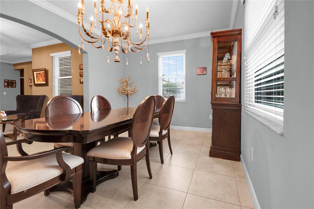 A dining room features a wooden table, upholstered chairs, a chandelier, and a display cabinet — 1301 GLENEAGLES LANE, DAVENPORT, FL