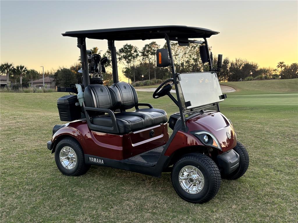 A maroon Yamaha golf cart is parked on a grassy golf course at sunset — 1301 GLENEAGLES LANE, DAVENPORT, FL