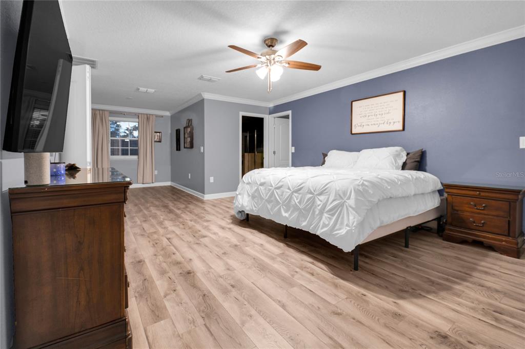 A bedroom features light wood flooring, a blue accent wall, and a white bed — 1301 GLENEAGLES LANE, DAVENPORT, FL
