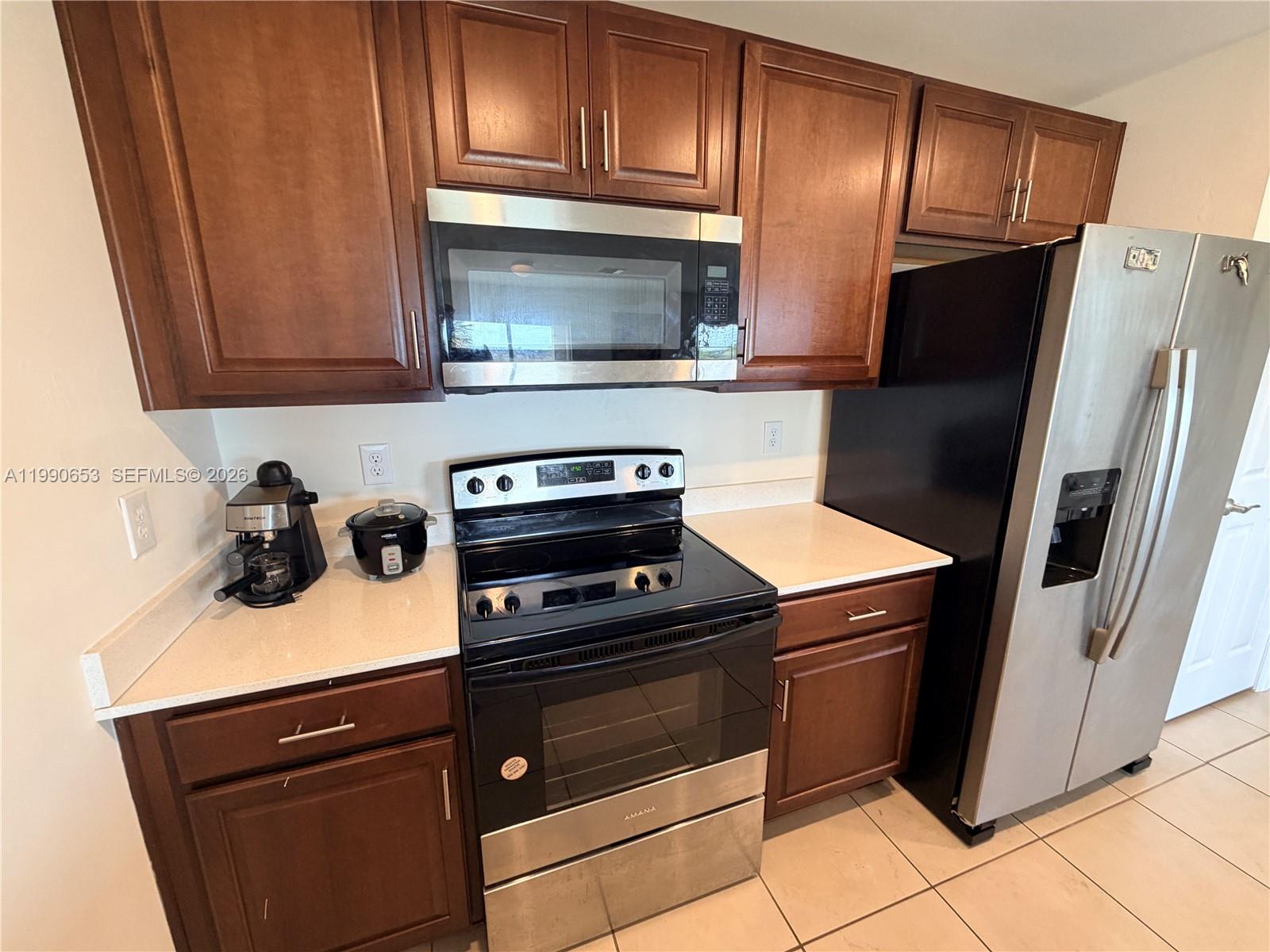 A kitchen features dark wood cabinets, stainless steel appliances, and light-colored countertops — 513 Ella Jean PL, La Belle FL 33935, LA BELLE, FL