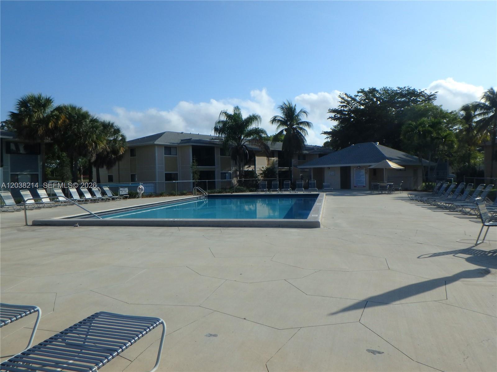 An outdoor swimming pool is surrounded by a concrete deck with lounge chairs and palm trees — 9727 Hammocks Blvd # 101D, Miami FL 33196, MIAMI, FL