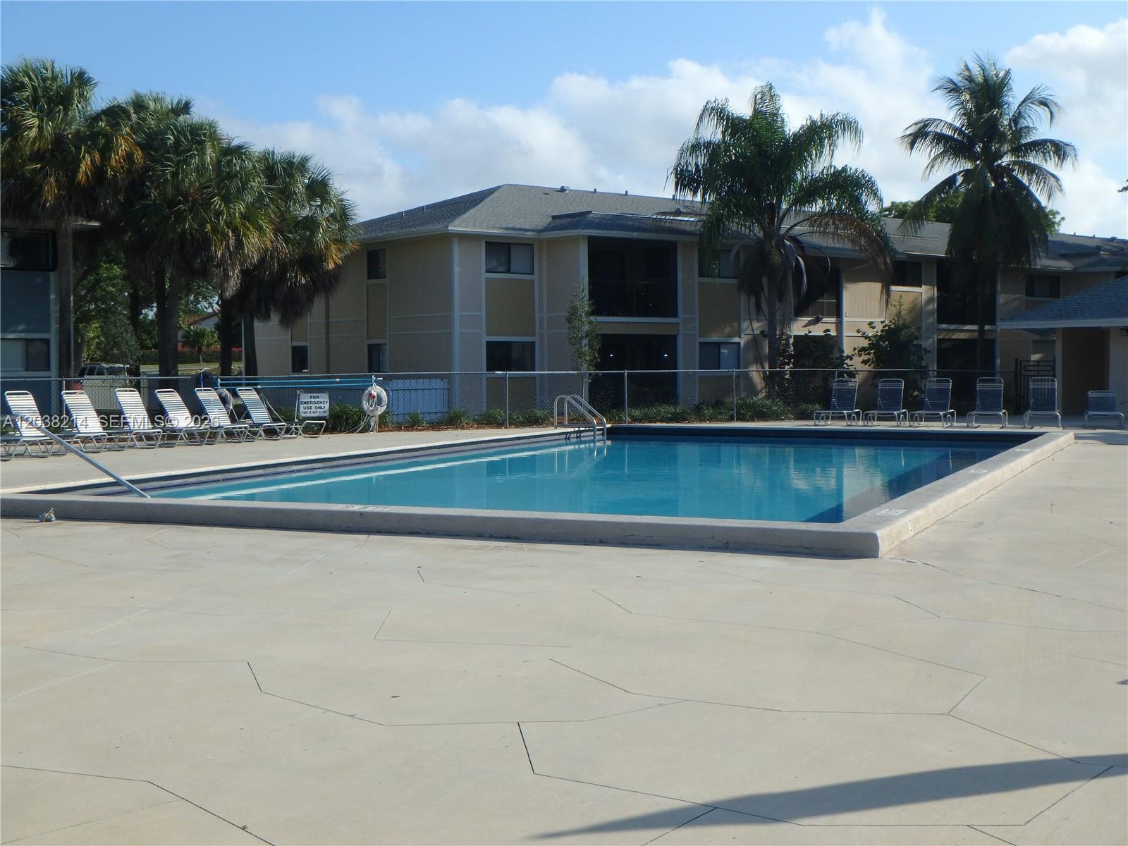 A rectangular swimming pool sits on a concrete deck in front of a multi-story building — 9727 Hammocks Blvd # 101D, Miami FL 33196, MIAMI, FL
