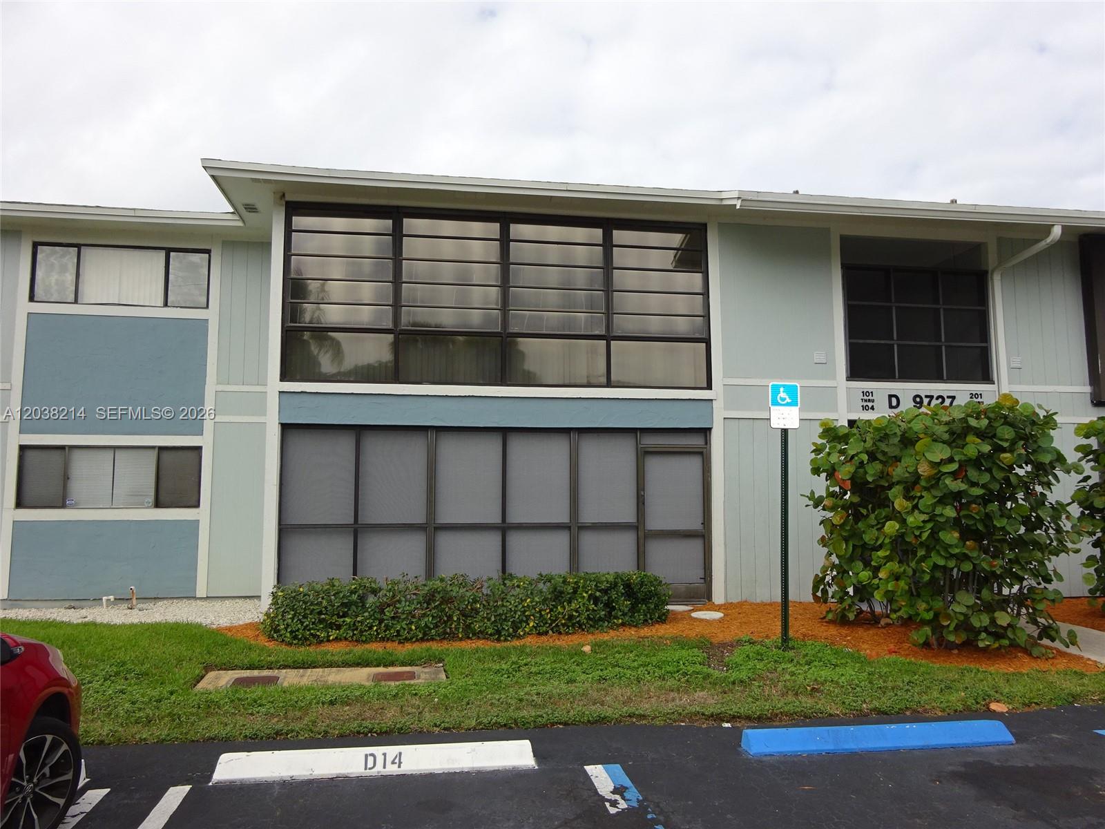 A two-story apartment building exterior features a screened-in ground floor patio and large windows — 9727 Hammocks Blvd # 101D, Miami FL 33196, MIAMI, FL