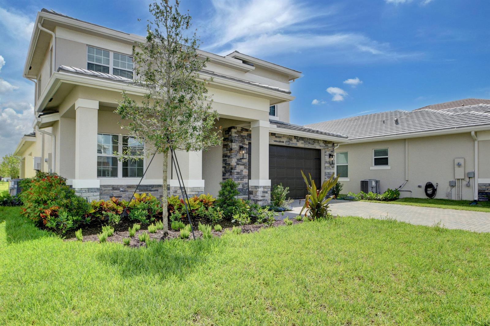 A two-story house with a stone facade, a paved driveway, and a landscaped front yard — 1366 Harvester Crossing, FL 33470, FL