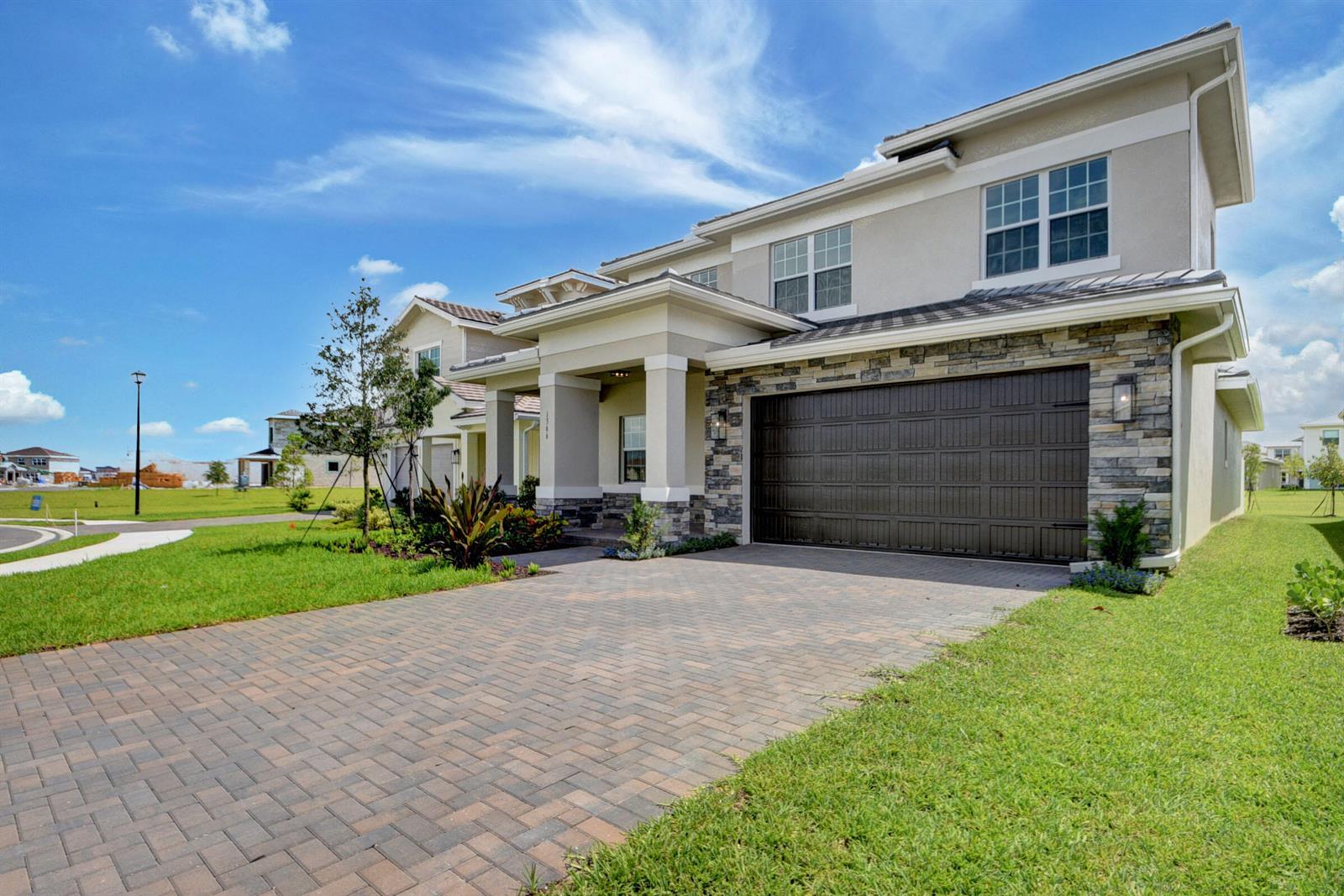 A two-story suburban house with a stone facade, a paved driveway, and a two-car garage — 1366 Harvester Crossing, FL 33470, FL