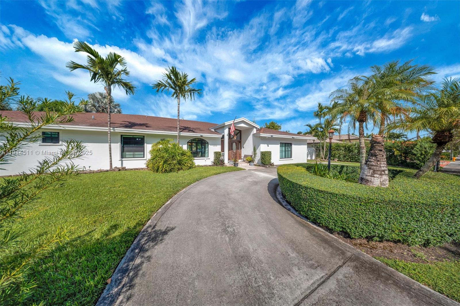 A white single-story house features a curved driveway, manicured hedges, and several palm trees — 10195 NW 26th St, Doral FL 33172, DORAL, FL
