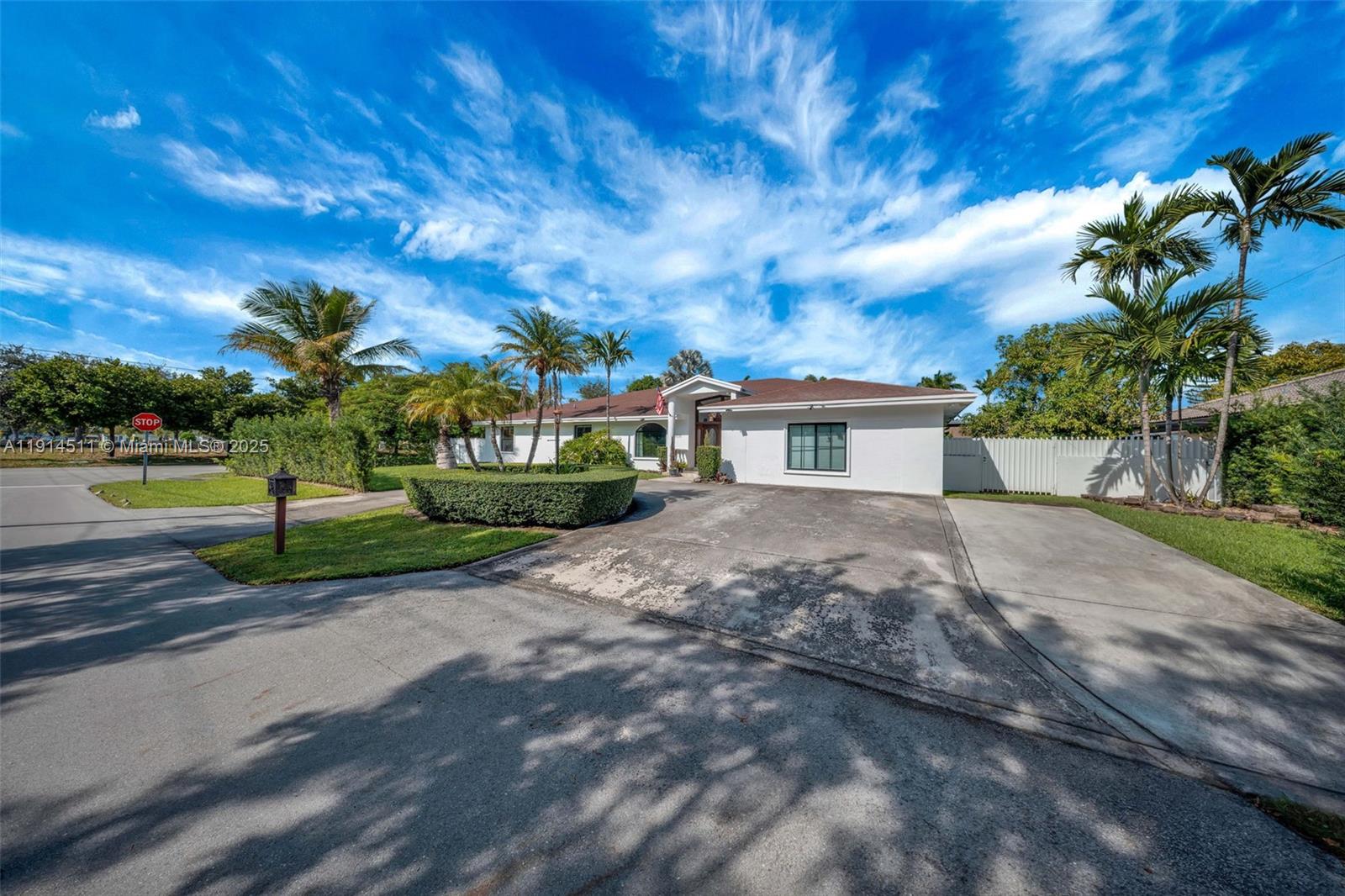 A white single-story house with a concrete driveway and palm trees under a blue sky — 10195 NW 26th St, Doral FL 33172, DORAL, FL