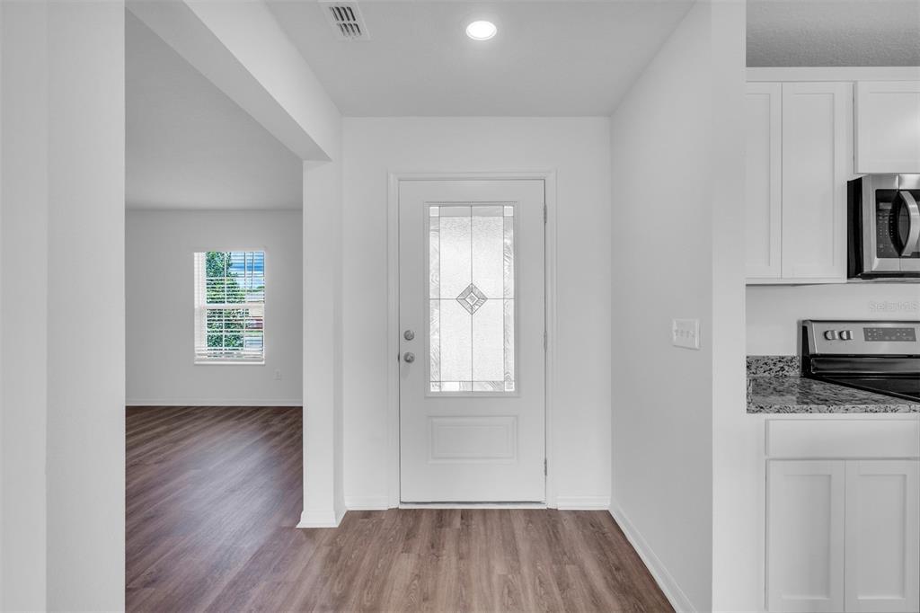 An entryway features a white front door, wood-look flooring, and an adjacent kitchen area — 40 PRESIDENTIAL LANE, PALM COAST, FL