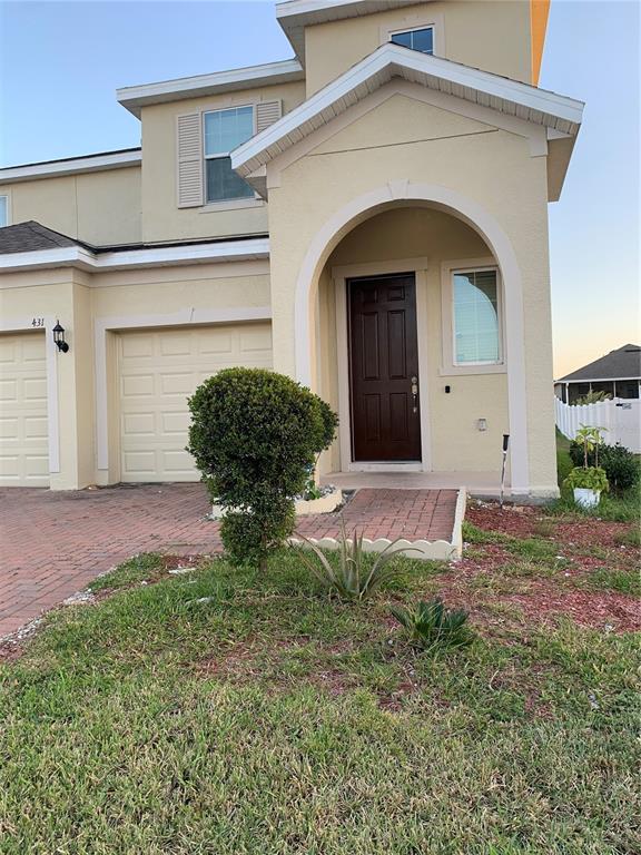 The exterior of a two-story beige house features a brick driveway, garage, and arched entryway — 431 ARAGOSA DRIVE, DAVENPORT, FL