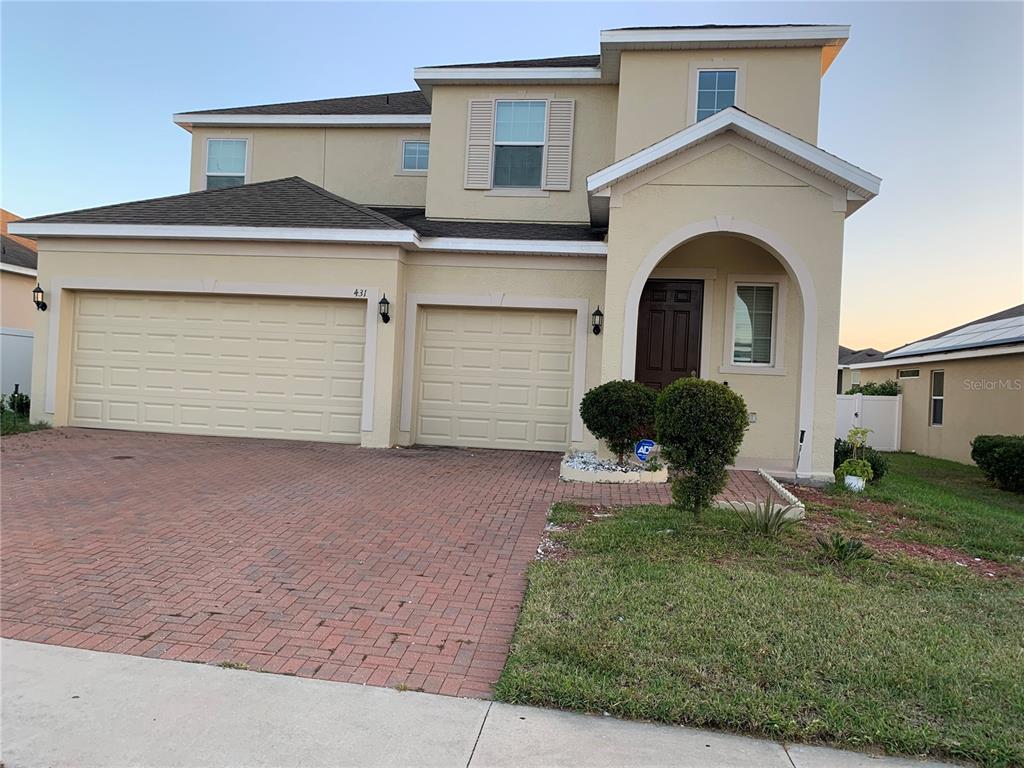A two-story house features a brick driveway, a two-car garage, and a covered entryway — 431 ARAGOSA DRIVE, DAVENPORT, FL
