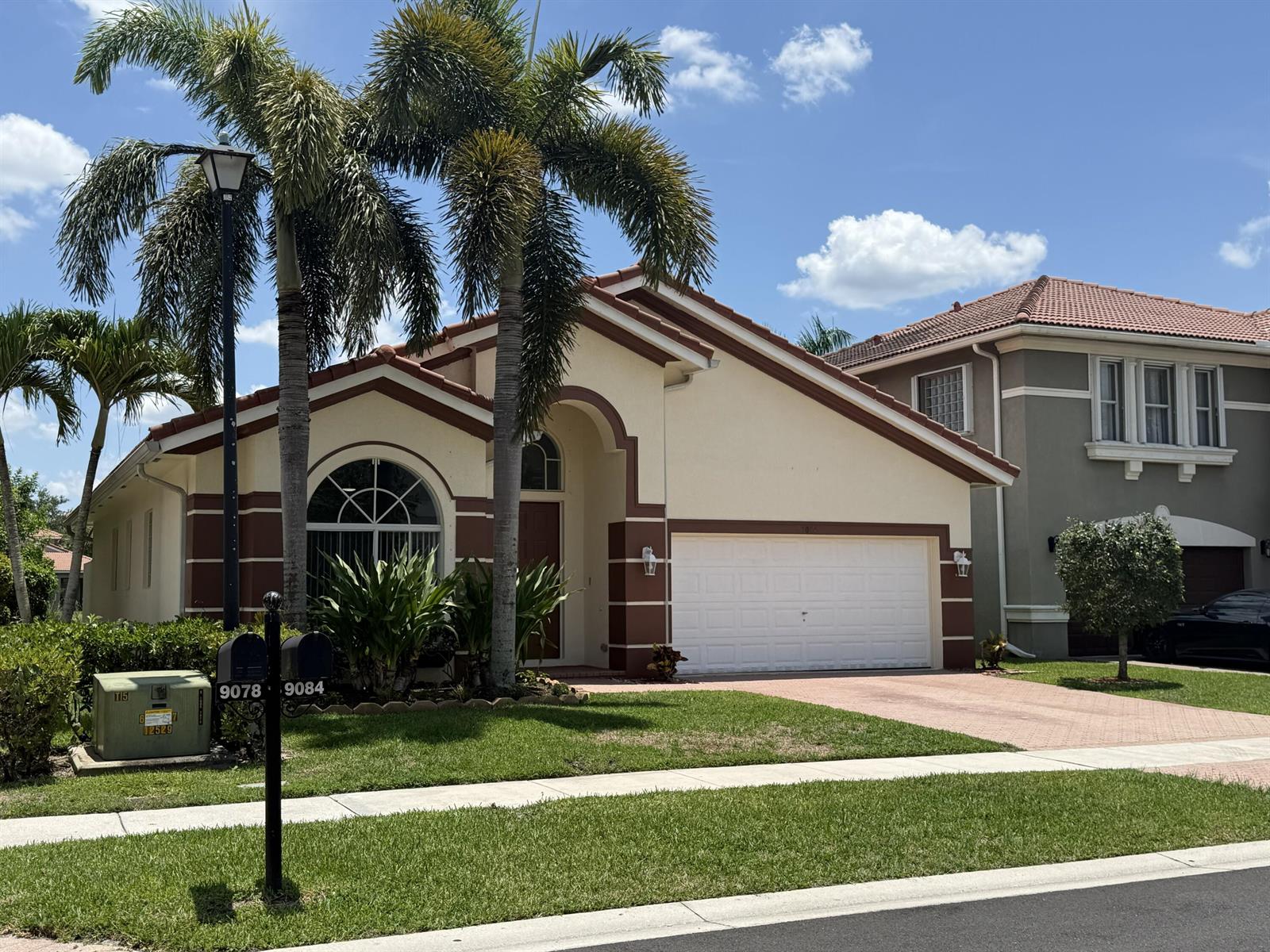 A single-story house with a white garage, arched window, and palm trees in the front yard — 9084 Silver Glen Way, Lake Worth FL 33467, LAKE WORTH, FL