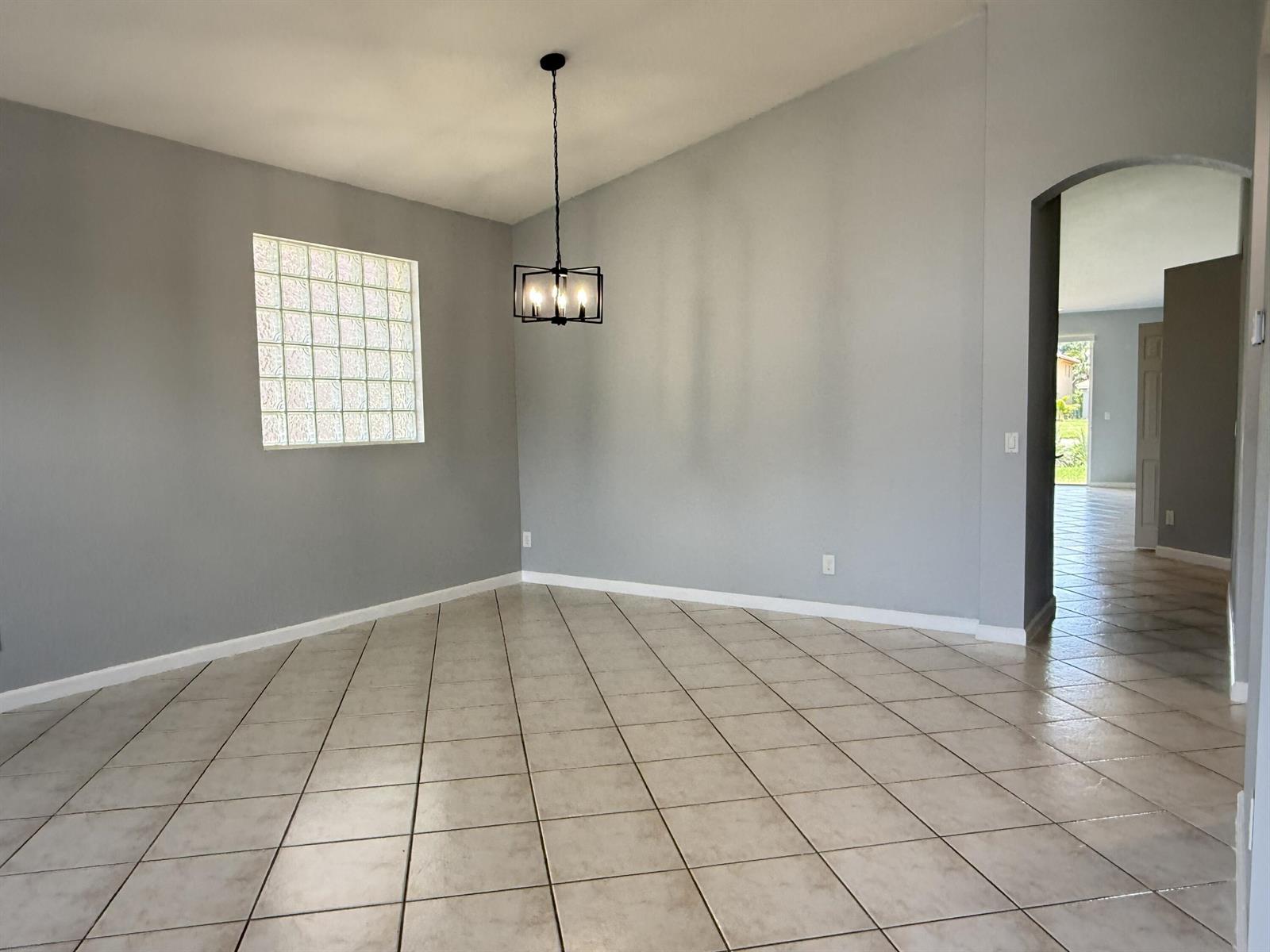 A dining room with gray walls, tile flooring, a glass block window, and a pendant light — 9084 Silver Glen Way, Lake Worth FL 33467, LAKE WORTH, FL