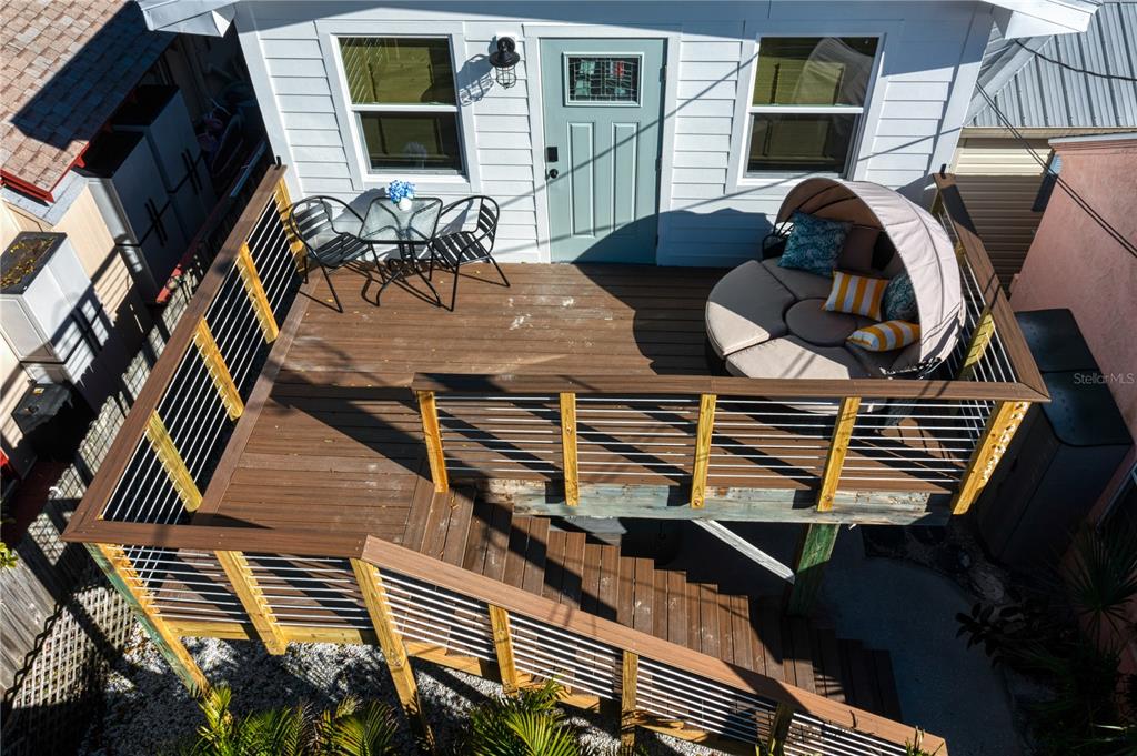 An elevated wooden deck features a small dining set, a round daybed, and metal railings — 800 GULF BOULEVARD UNIT 5, INDIAN ROCKS BEACH, FL